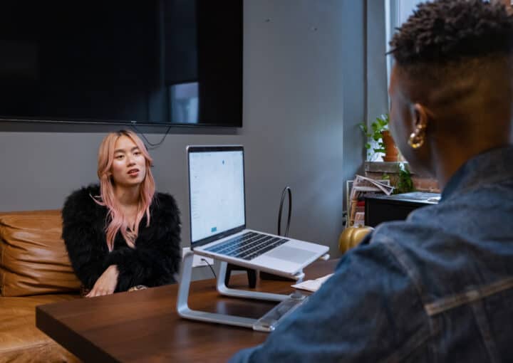 Recrutement inclusif - 2 personnes discutent dans un bureau, l'une est de dos et l'autre est de face, assise sur un canapé.